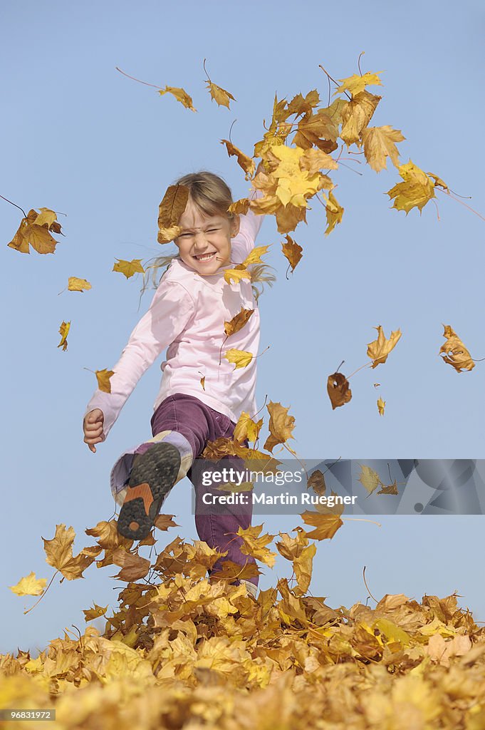 Girl (7 years) kicking leaves