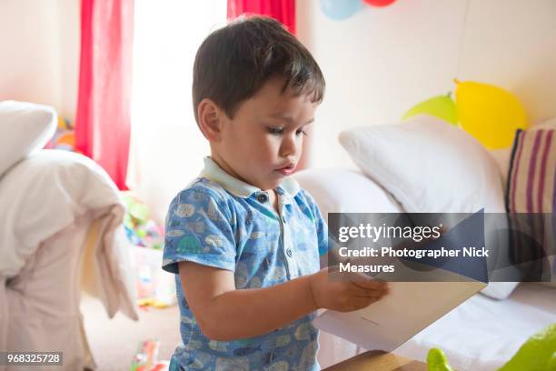 two year old birthday boy pretending to read his card. - stroud gloucestershire stock pictures, royalty-free photos & images