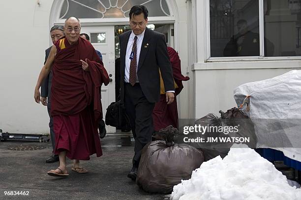 Exiled Tibetan spiritual leader the Dalai Lama walks out the doors of the Palm Room of the White House by trash bags waiting to be picked up due to...