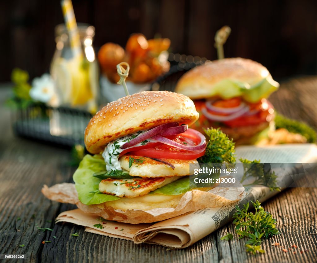 Halloumi burger with fresh lettuce, tomato, cucumber and onion with the addition of yoghurt mint sauce on a wooden rustic table. Vegetarian food