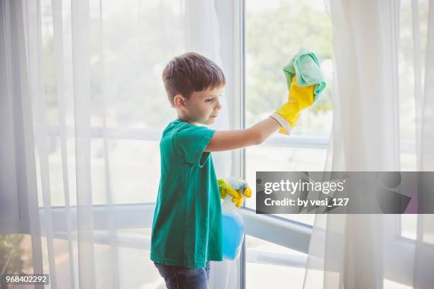 cute little boy cleaning windows - kids with cleaning rubber gloves stock-fotos und bilder