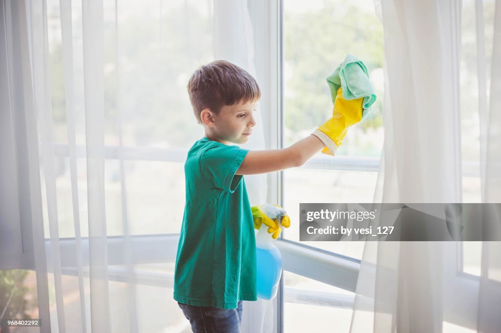 Cute little boy cleaning windows