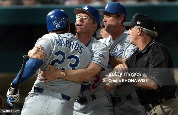 Los Angeles Dodgers manager Jim Tracy holds back first baseman Eric Karros with the help of first base umpire Mike Reilly and third base coach Glenn...