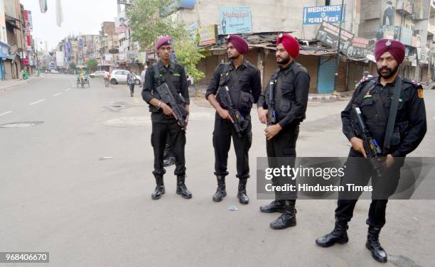 Security personnel stand alert outside closed shops at hall bazaar during a shutdown call given by radical Sikh organization 'Dal Khalsa' on the 34th...