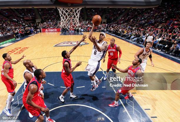 Courtney Lee of the New Jersey Nets goes up for a shot against Louis Williams, Marreese Speights and Willie Green of the Philadelphia 76ers during...