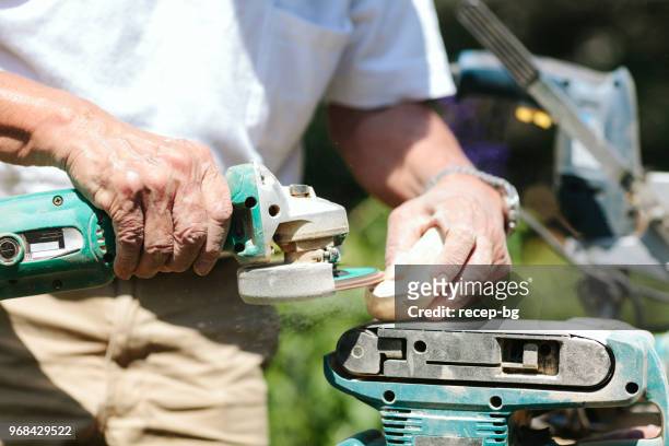 close-up photo of hands of senior man while making craft from wood - park man made space stock pictures, royalty-free photos & images