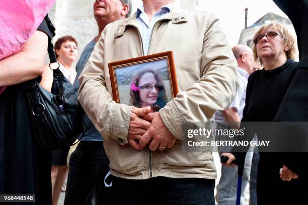 Man holds a picture of murdered French au-pair Sophie Lionnet after her funeral in Sens on June 6, 2018. - A French couple was on May 24, 2018 found...