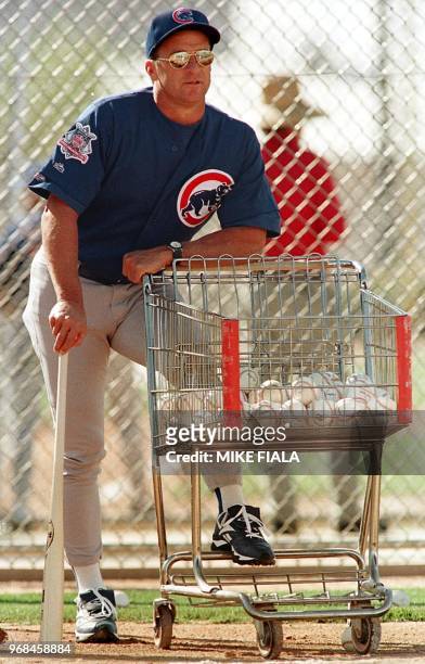 Chicago Cubs manager Jim Riggleman rests on a shopping cart filled with baseballs while watching his squad during spring training 21 February in...