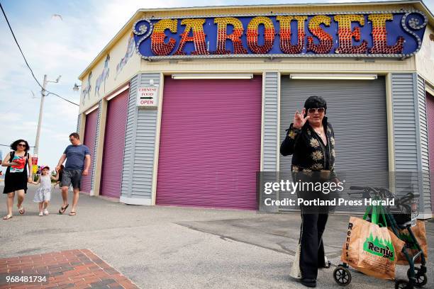 Elivis impersonator Donald Bolduc pauses for a photograph on his way to the corner of Old Orchard Beach Street and West Grand Avenue, where he has...