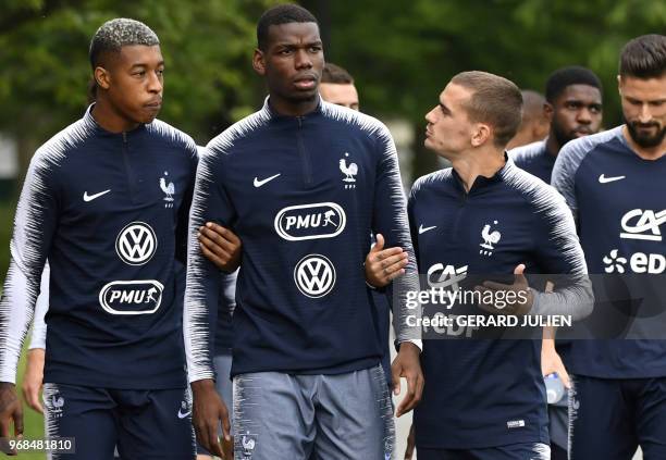 France's defender Presnel Kimpembe and foward Antoine Griezmann hold by the arms midfielder Paul Pogba as they arrive for a training session at the...