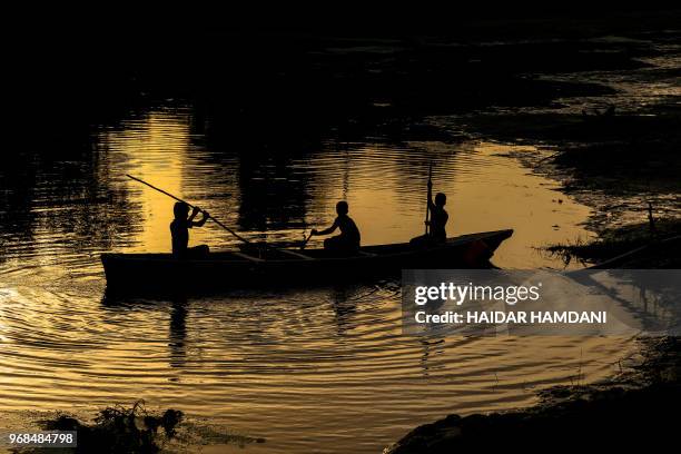 Iraqi children move around in a boat in the Mishkhab region, some twenty-five kilometers from Najaf, on June 6, 2018. - This traditional region of...