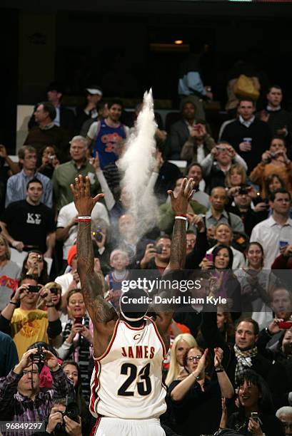 LeBron James of the Cleveland Cavaliers tosses talc powder high into the air as part of his routine before the game against the Denver Nuggets on...