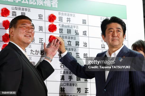 Le Premier ministre du Japon et chef du Parti liberal, Shinzo Abe et Shigeru Ishiba , posent une rose sur le nom du candidat vainqueur lors du...