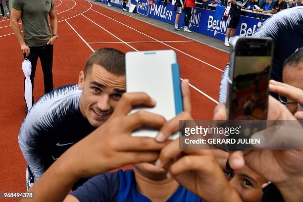 French forward Antoine Griezmann poses for pictures with a fan during a training session at the French national football team's training grounds in...