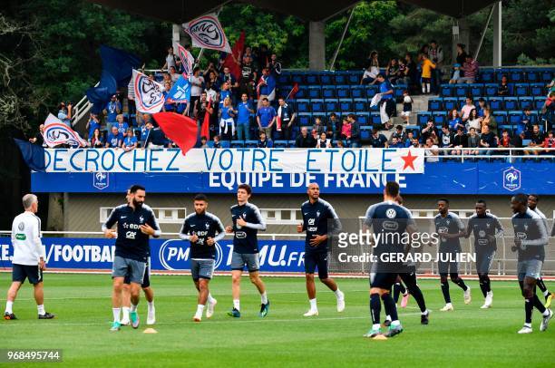 France's fans support, cheer and hold a placard reading "get your star" as they watch France's national football players taking part in a training...