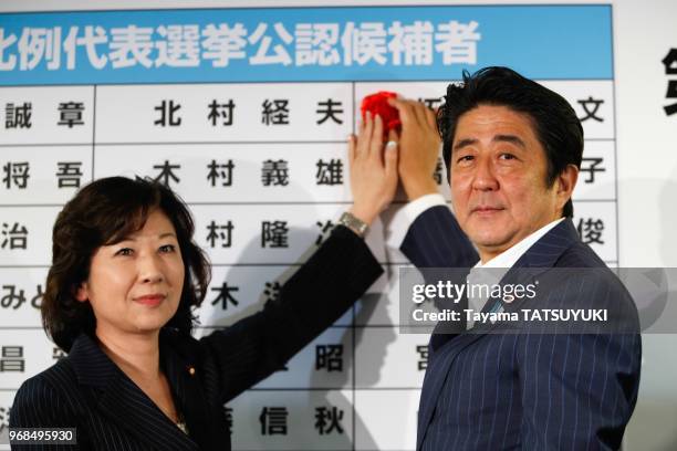 Le Premier ministre du Japon et chef du Parti liberal, Shinzo Abe et Seiko Noda , posent une rose sur le nom du candidat vainqueur lors du...