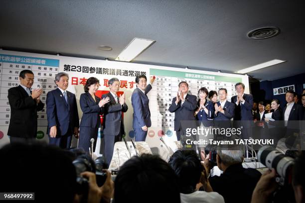 Le Premier ministre du Japon et chef du Parti liberal, Shinzo Abe avec les officiels du parti, pose une rose sur le nom du candidat vainqueur lors du...