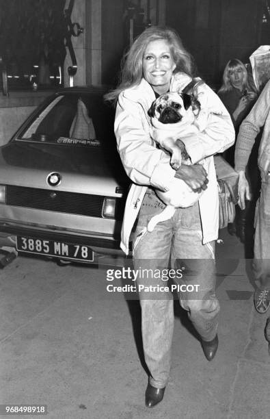 Portrait de la chanteuse Dalida portant son chien à son arrivée à l'Olympia le 20 mars 1981 à Paris, France.