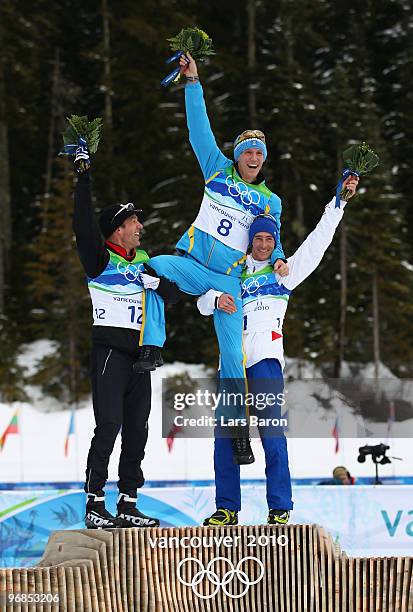 Christoph Sumann of Austria celebrates winning silver, Bjorn Ferry of Sweden gold and Vincent Jay of France bronze during the flower ceremony for the...