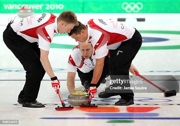 Skip Kevin Martin of Canada delivers as Marc Kennedy and Ben Hebert sweep during the curling round robin game against France on day 7 of the...