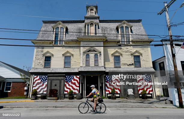 Vinalhaven resident Chuck Clapham rides his bike past Robert Indiana's Vinalhaven home, the former Odd Fellows Hall named Star of Hope Wednesday, May...