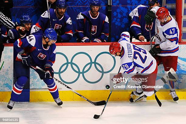 Andrej Sekera of Slovakia srambles for the puck along the boards with Sergey Fedorov of Russia during the ice hockey men's preliminary game between...