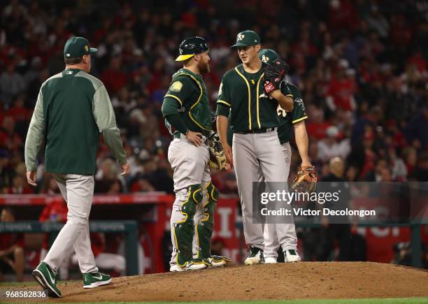 Catcher Jonathan Lucroy of the Oakland Athletics talks to pitcher Daniel Gossett as manager Bob Melvin approaches the mound in the fourth inning of...