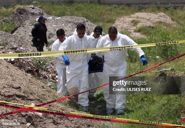 Ministerial police officers carry a body found in a clandestine common grave, at the Lomas del Aeropuerto neighborhood in El Salto municipality,...