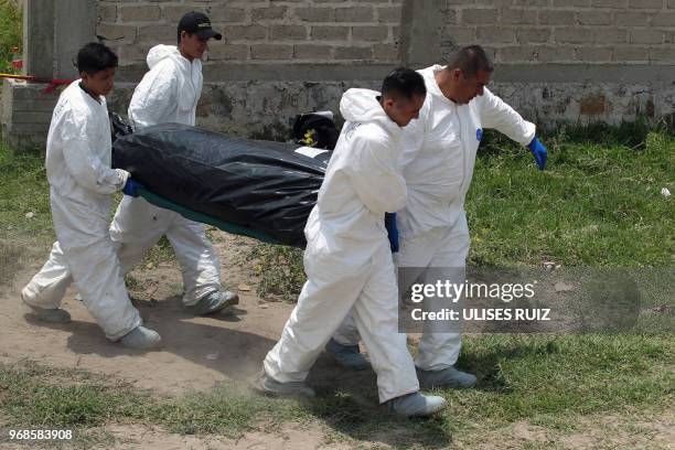 Ministerial police officers carry a body found in a clandestine common grave, at the Lomas del Aeropuerto neighborhood in El Salto municipality,...