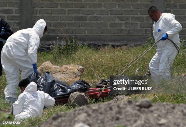 Ministerial police officers work to move a body from a clandestine common grave, at the Lomas del Aeropuerto neighborhood in El Salto municipality,...