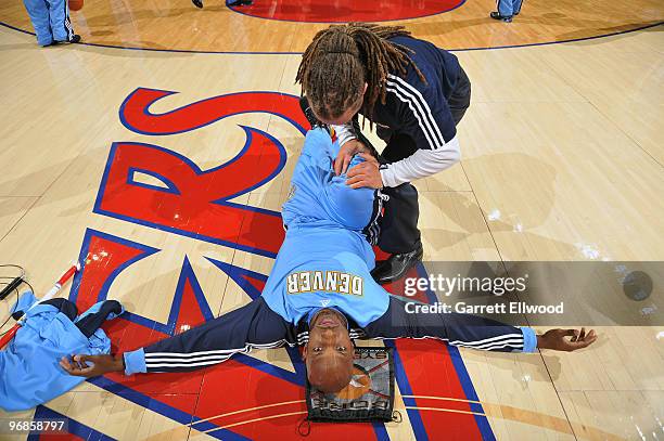 Strength and conditioning coach Steve Hess stretches Chauncey Billups of the Denver Nuggets prior to the game against the Cleveland Cavaliers on...