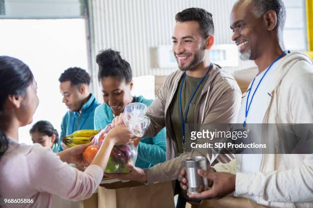 fröhliche freiwilligen erhalten spenden während nahrungsmittel-antrieb - homelessness stock-fotos und bilder