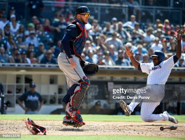 Jose Pirela of the San Diego Padres slides as he scores in front of Tyler Flowers of the Atlanta Braves during the eighth inning of a baseball game...
