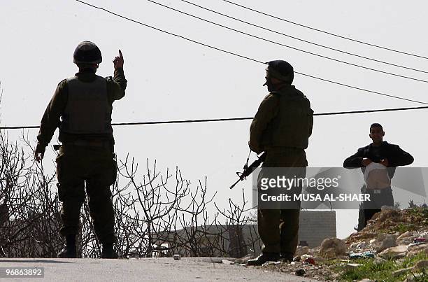An Israeli soldier gives an order to a Palestinian protester to lift his shirt during a demonstration against Israel's separation barrier, in the...