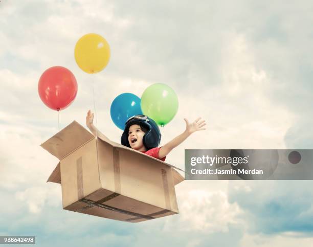 kid flying in cardboard box with balloons between clouds - balloon kid stock pictures, royalty-free photos & images
