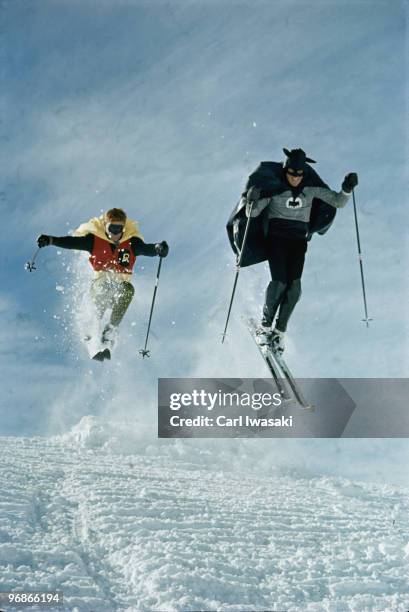 Ski instructor Roger Staub and patrol member Chuck Malloy race down slope in Batman and Robin costumes. Vail, Colorado 1966.