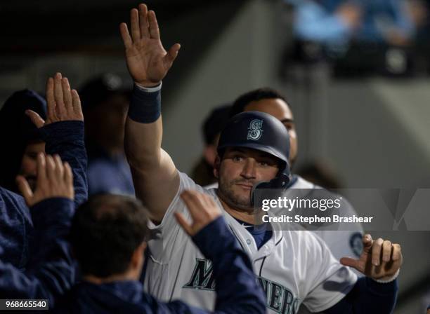 Mike Zunino of the Seattle Mariners is congratulated by teammates in the dugout after scoring a run during a game against the Texas Rangers at Safeco...