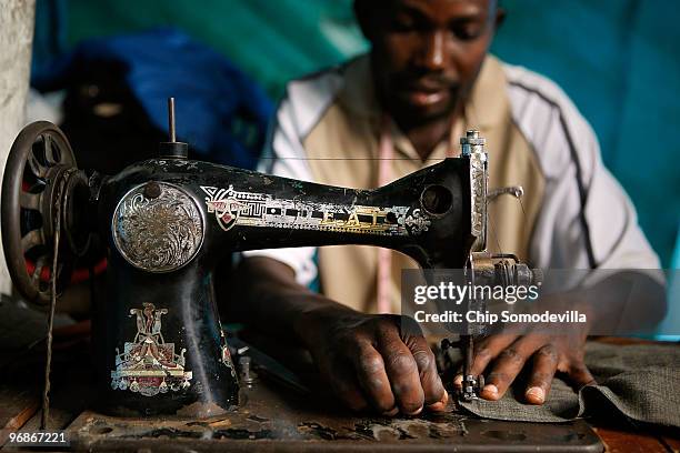 Cantain Saint-Hilaire works on the sewing machine he salvaged from his earthquake-destroyed tailor shop inside his tent at the Route de Piste camp, a...