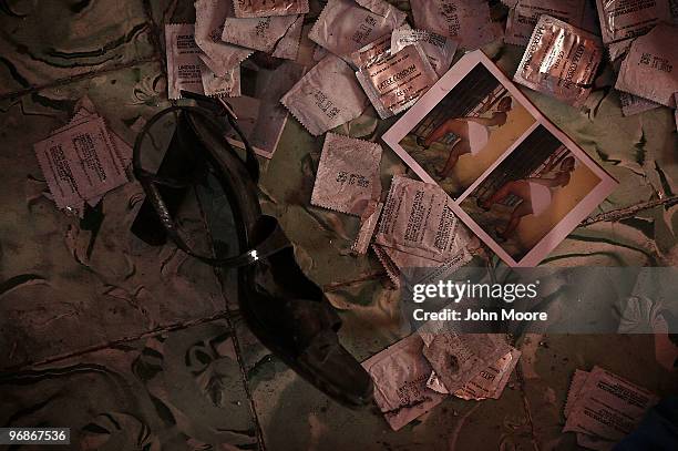 Photos, condoms and a shoe lie scattered on a bedroom floor in the Belle Haiti brothel on February 12, 2010 in Port-au-Prince, Haiti. Two prostitutes...