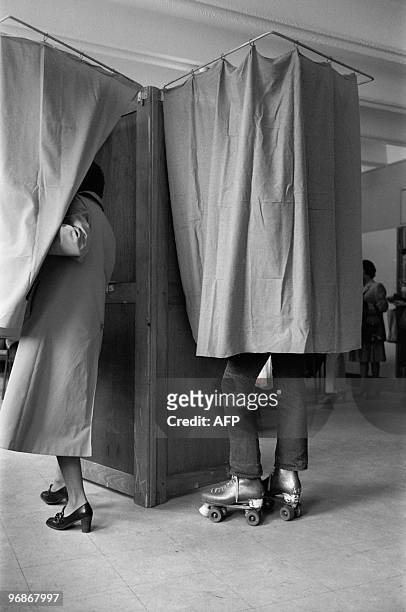 French young voter with roller-skates prepares her ballot in a booth at a Paris polling station on May 10, 1981 for the second round of the...
