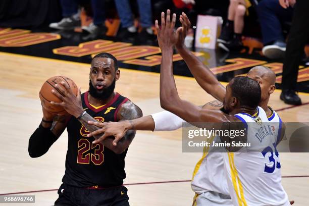 LeBron James of the Cleveland Cavaliers drives to the basket defended by Kevin Durant and David West of the Golden State Warriors in the first half...