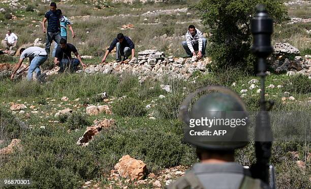 Palestinian demonstrators collect stones as they clash with Israeli forces on February 5, 2010 after a weekly protest against Israeli settlement...