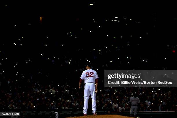 Fans shine the lights on their cell phones in the stands as Matt Barnes of the Boston Red Sox looks on during the seventh inning of a game against...