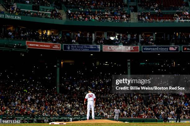 Fans shine the lights on their cell phones in the stands as Matt Barnes of the Boston Red Sox looks on during the seventh inning of a game against...