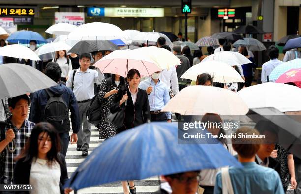 People holding umbrellas walk in front of Osaka Station on June 6, 2018 in Osaka, Japan. Japan Meteorological Agency said that compared with last...