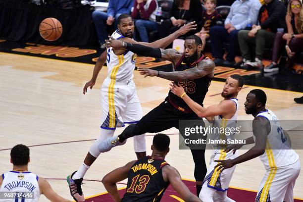 LeBron James of the Cleveland Cavaliers throws a pass around Stephen Curry and Kevin Durant of the Golden State Warriors in the first half during...