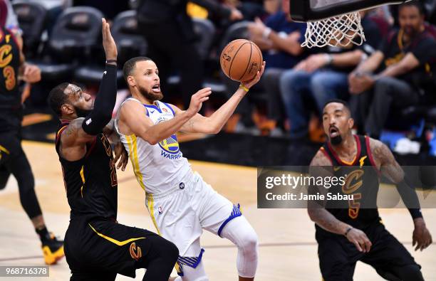 Stephen Curry of the Golden State Warriors attempts a layup defended by JR Smith and LeBron James of the Cleveland Cavaliers in the third quarter...