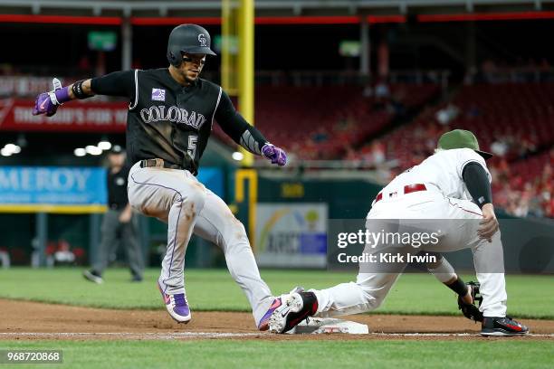 Carlos Gonzalez of the Colorado Rockies safely advances to third base on a wild pitch before Eugenio Suarez of the Cincinnati Reds can make the tag...