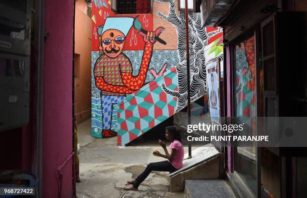 In this picture taken on June 1 an Indian girl sits near a mural in Mumbai. Mumbai's slums are getting a colourful makeover thanks to an organisation...