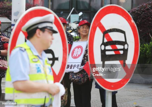 Security volunteers and police officers guard outside a school at the first day of the 2018 college entrance exam of China, or the "Gaokao", in...